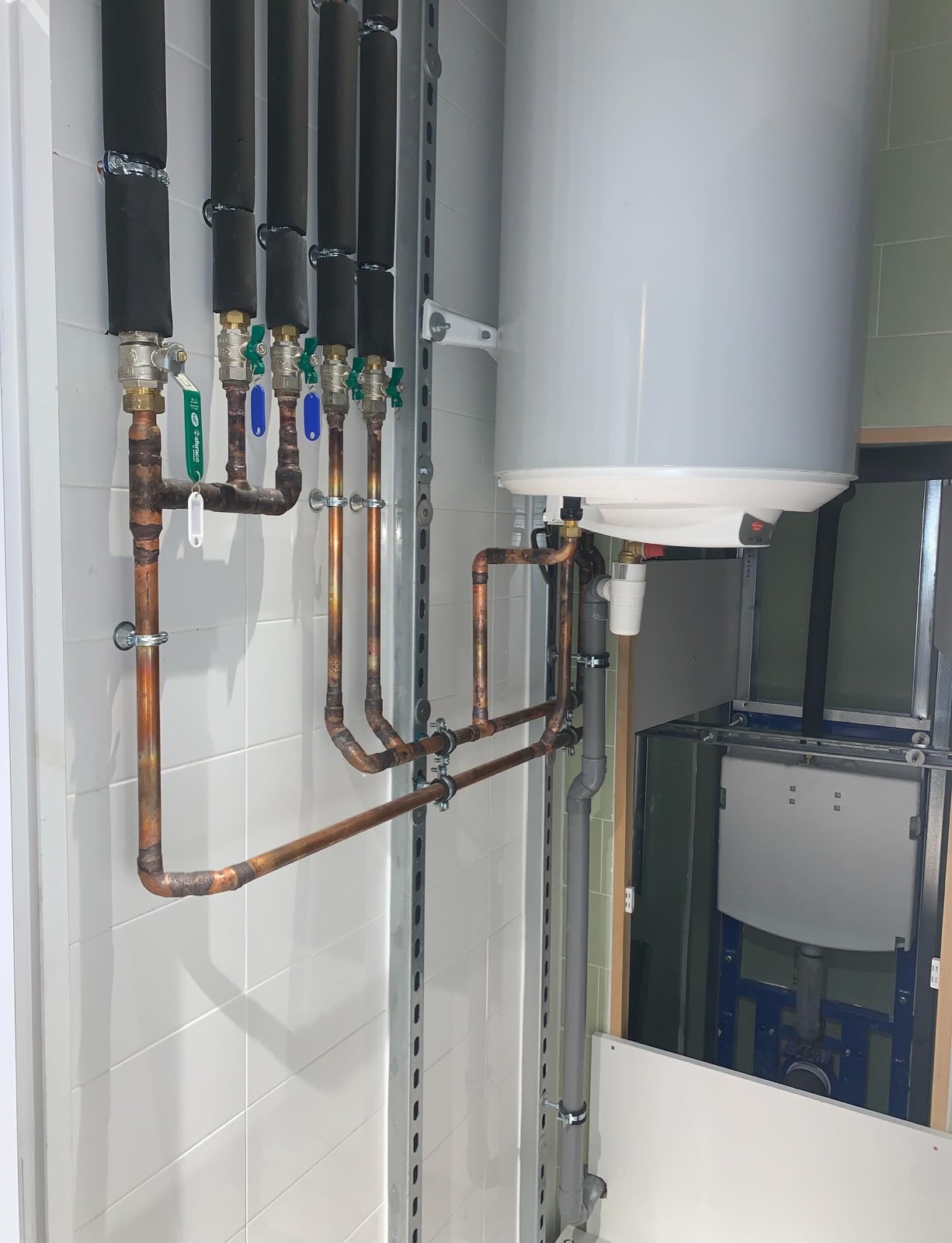 Chauffe-eau installé avec réseau cuivre neuf, vannes d'arrêt repérées et tubes calorifugés