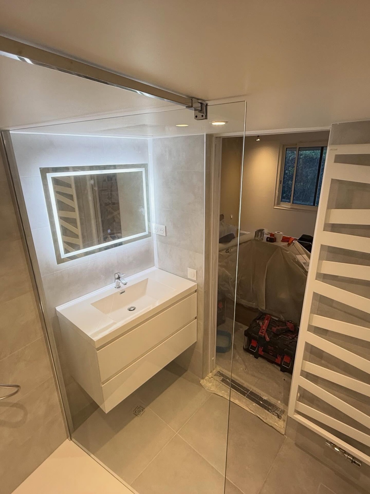 Finitions d'une salle de bain rénovée : meuble vasque suspendu, miroir LED et sèche-serviettes