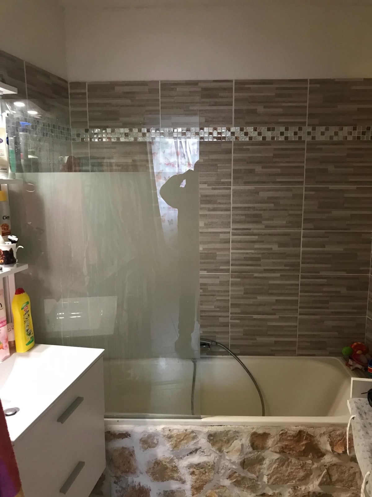 Salle de bain avant rénovation complète : baignoire habillée de pierre et carrelage vieillissant