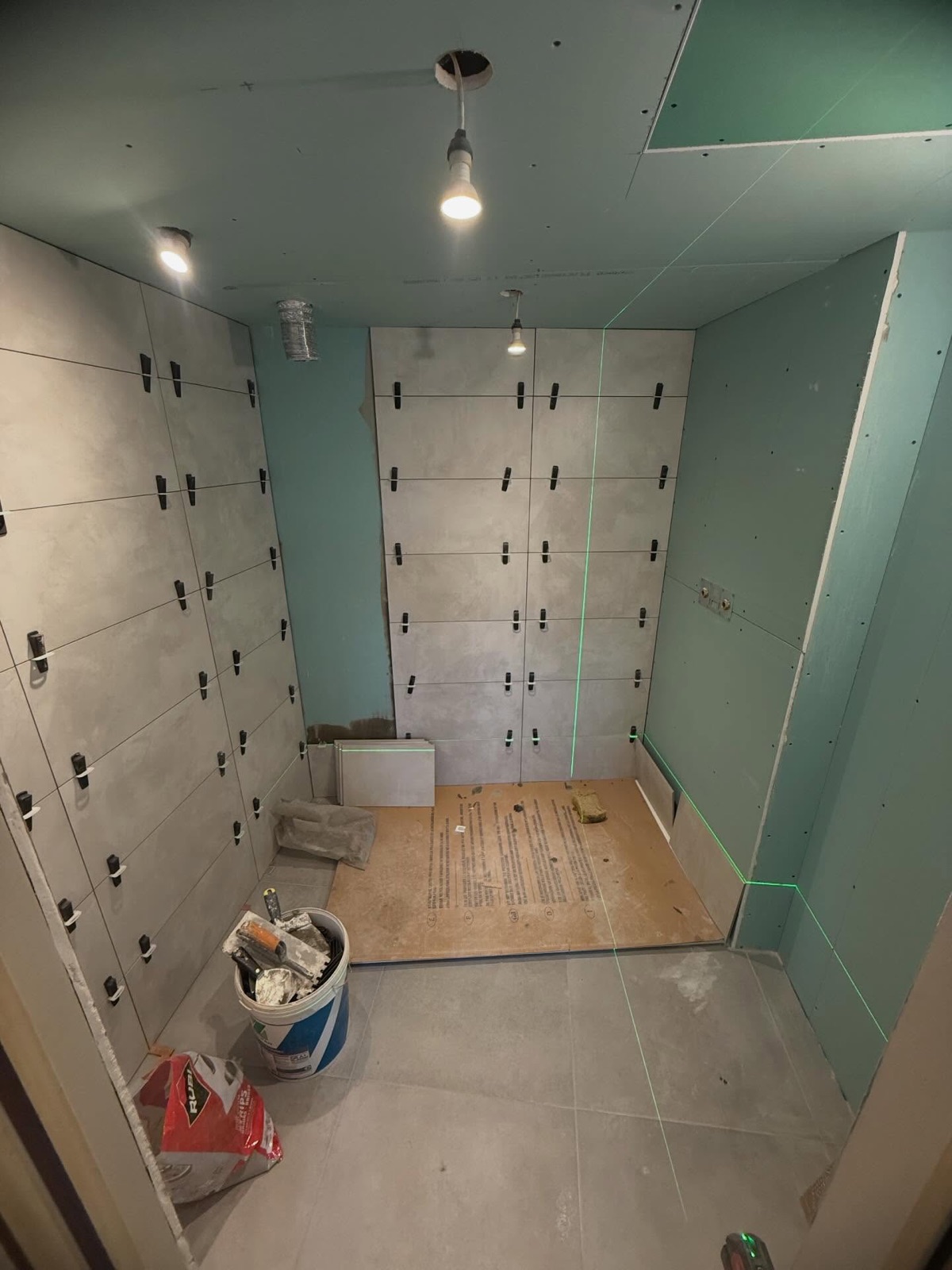 Pose de faïence grand format alignée au laser dans une douche à l'italienne